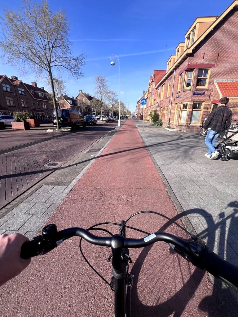 Handlebar view riding a red bike lane in Amsterdam