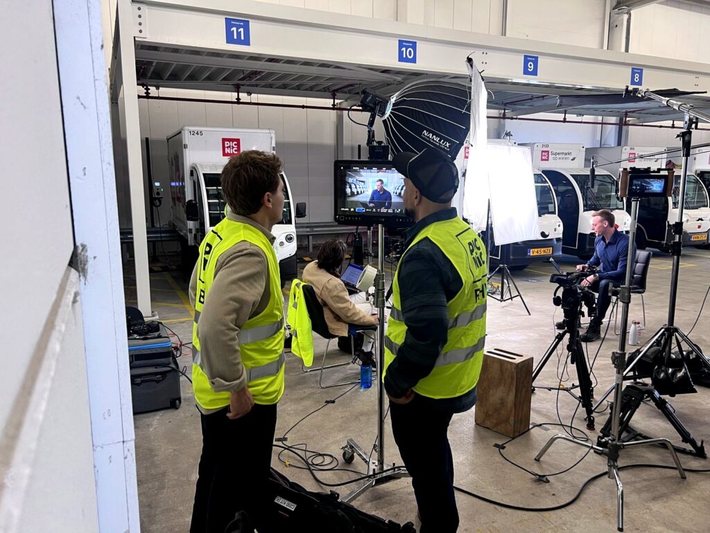 Arc Media crew in high-visibility vests working the interview setup inside the Picnic depot