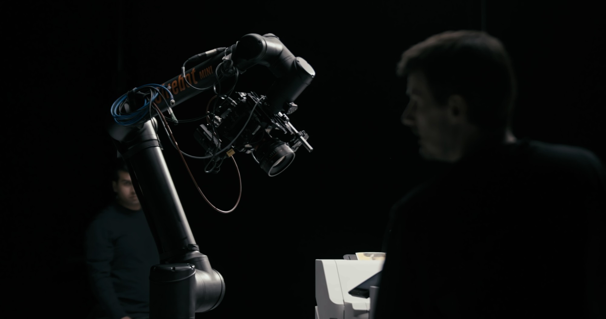The robotic arm in silhouette with a crew member watching the move