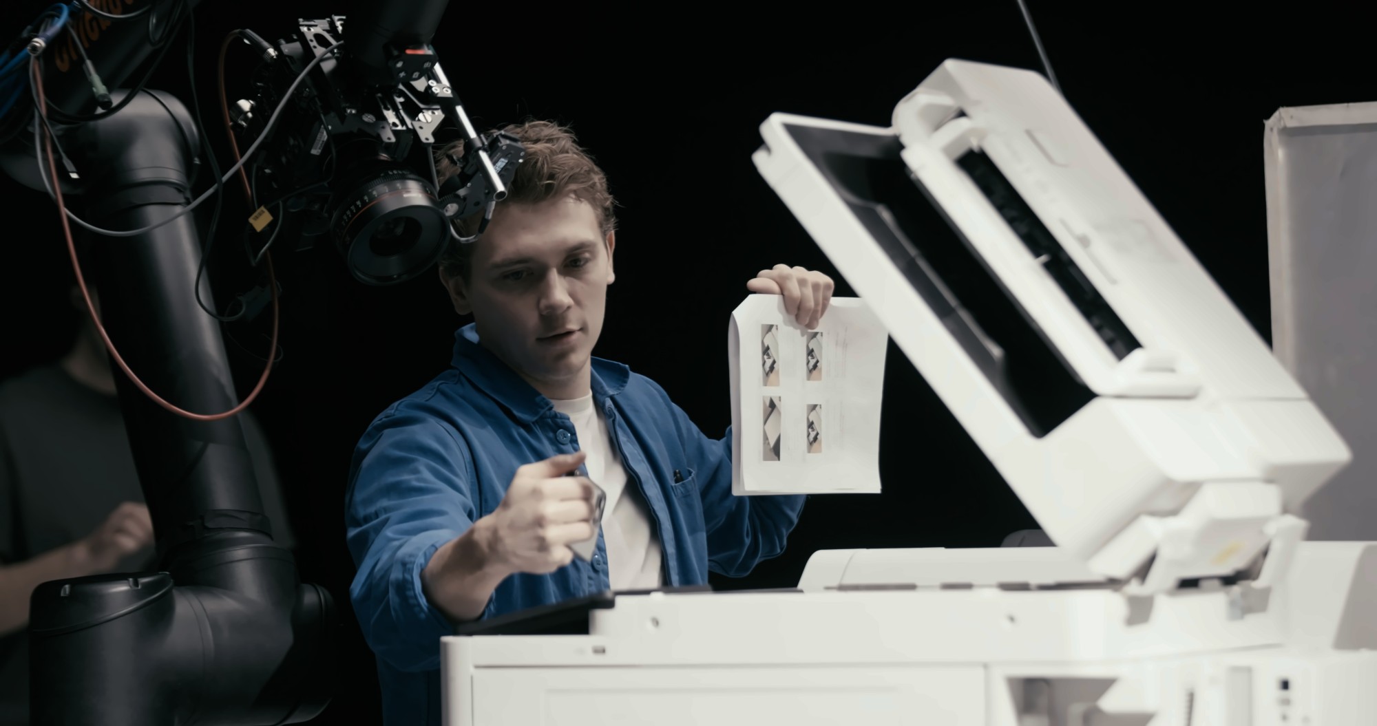 A crew member checking a printed sheet beside the printer